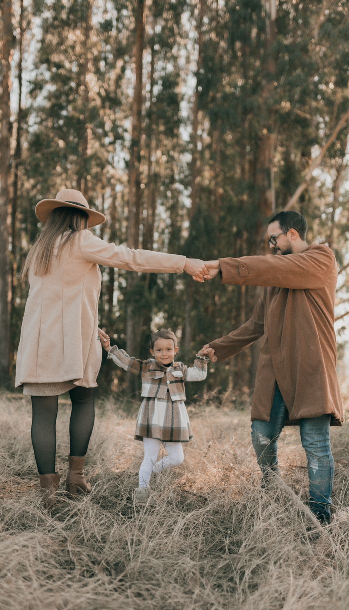 journey Happy family with child enjoying a sunny autumn day in the forest, holding hands and smiling.