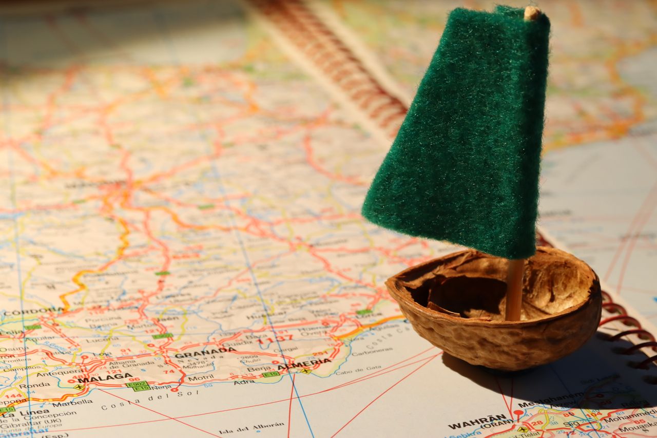 team-03 Creative travel metaphor with a tiny sailboat on a detailed world map.