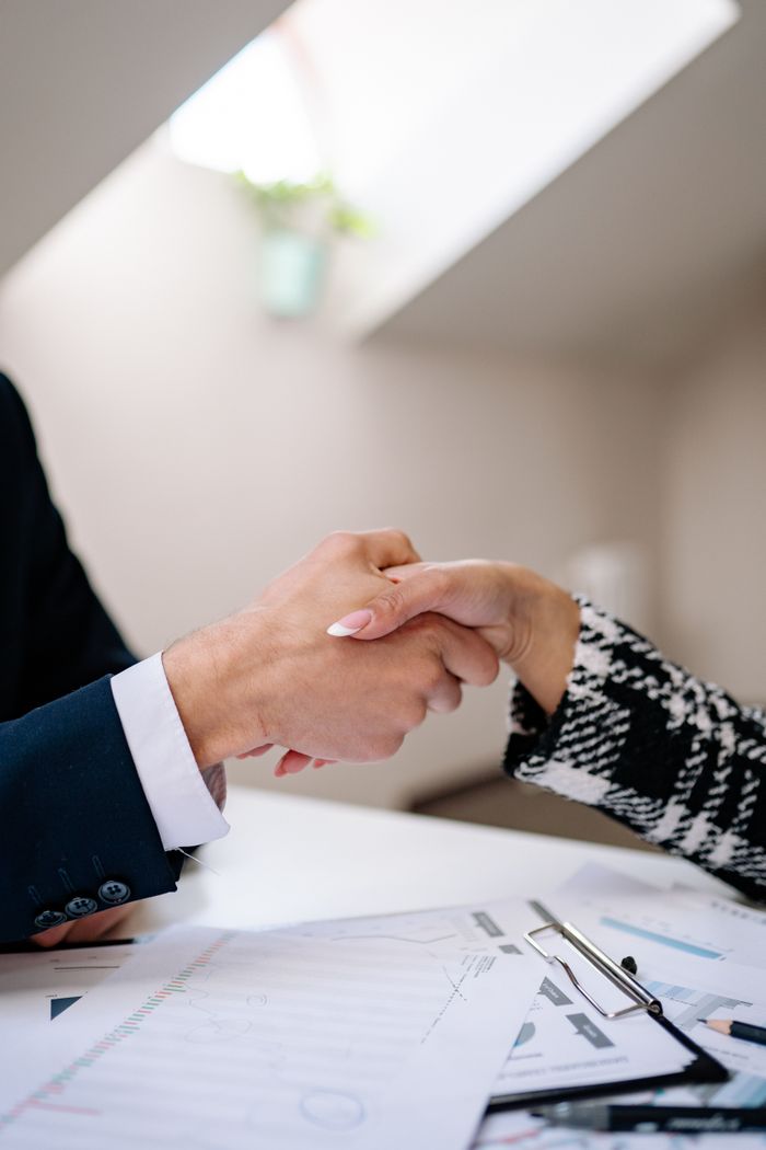 services-01 Close-up of a professional handshake between colleagues in a modern office setting, symbolizing agreement.